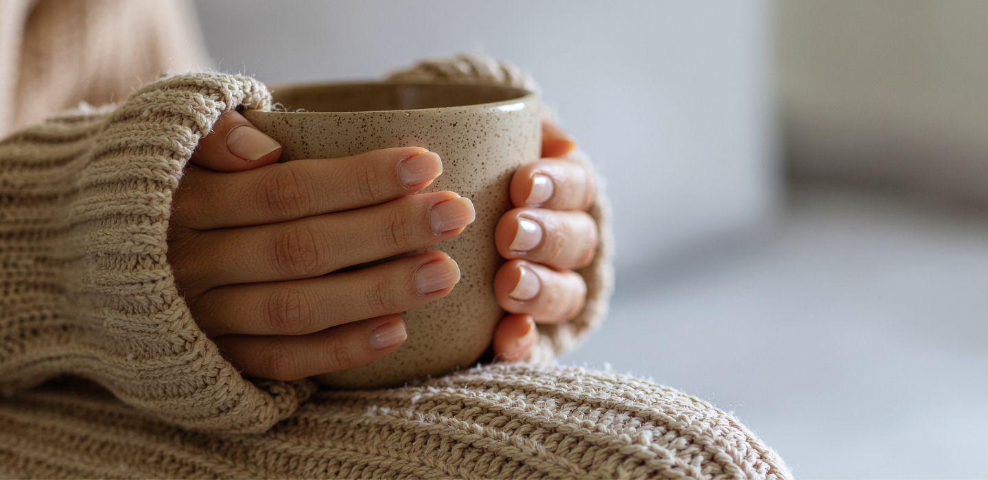 Hands wrapped around a warm ceramic mug.
